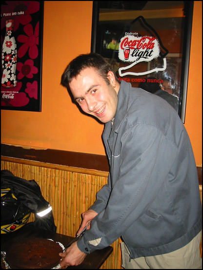 Kenneth cutting the cake in a bar across the street